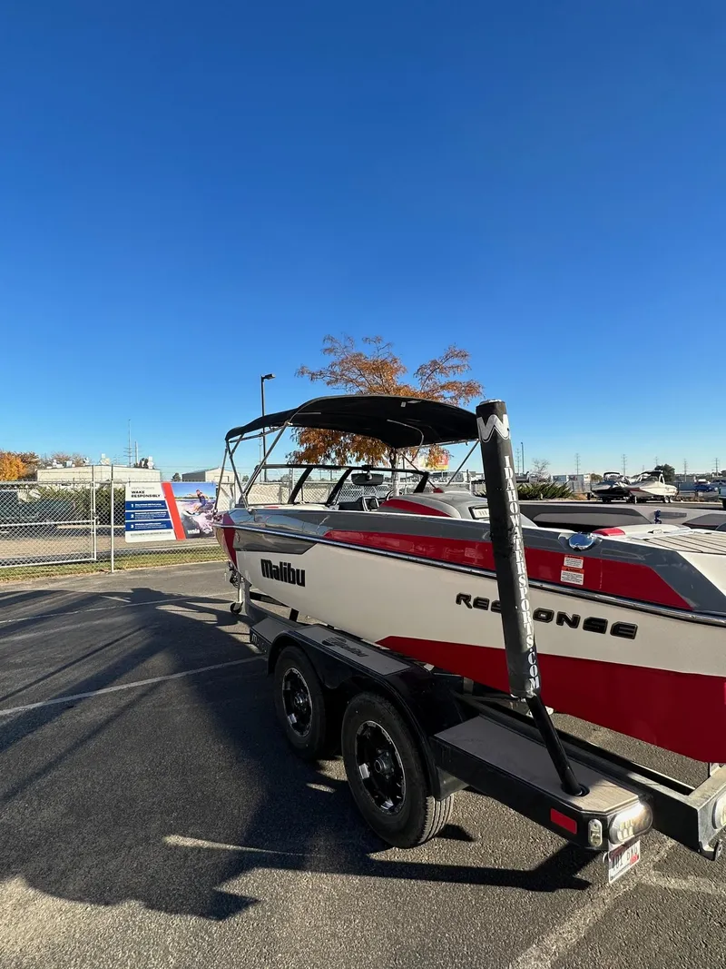 Slide: The Image of 2019 Malibu TXi Mo boat on trailer under clear blue sky. - 7