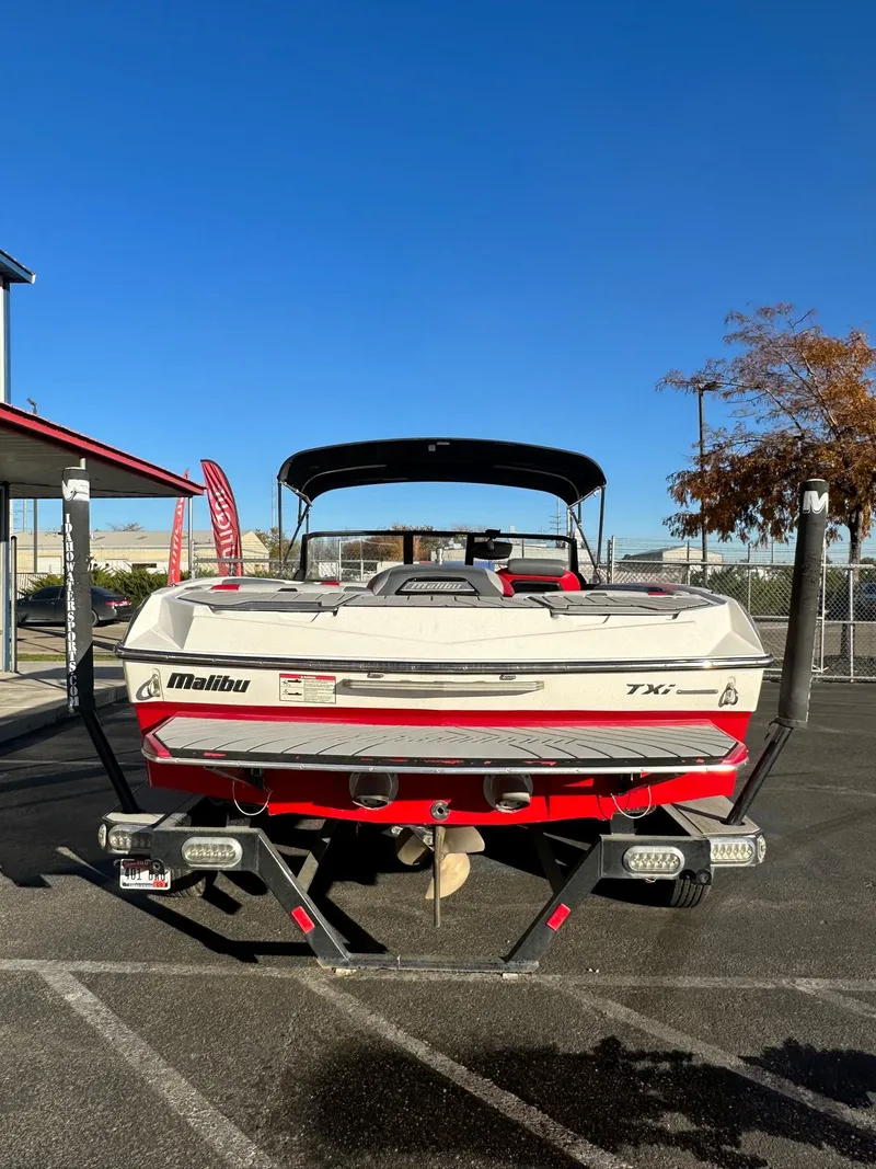 Slide: The Image of 2019 Malibu TXi Mo boat parked outdoors on a sunny day. - 8