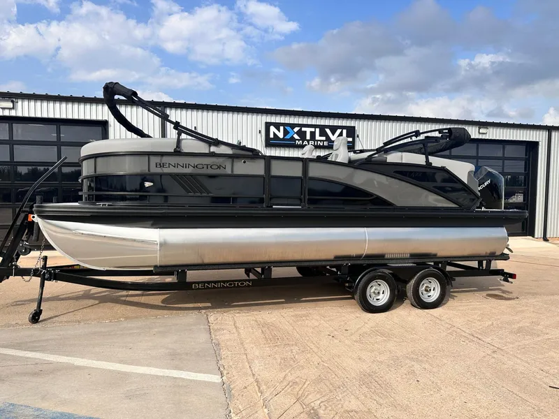 Slide: The Image of 2025 Bennington 22MFB pontoon boat on trailer, parked outside marine dealership. - 1