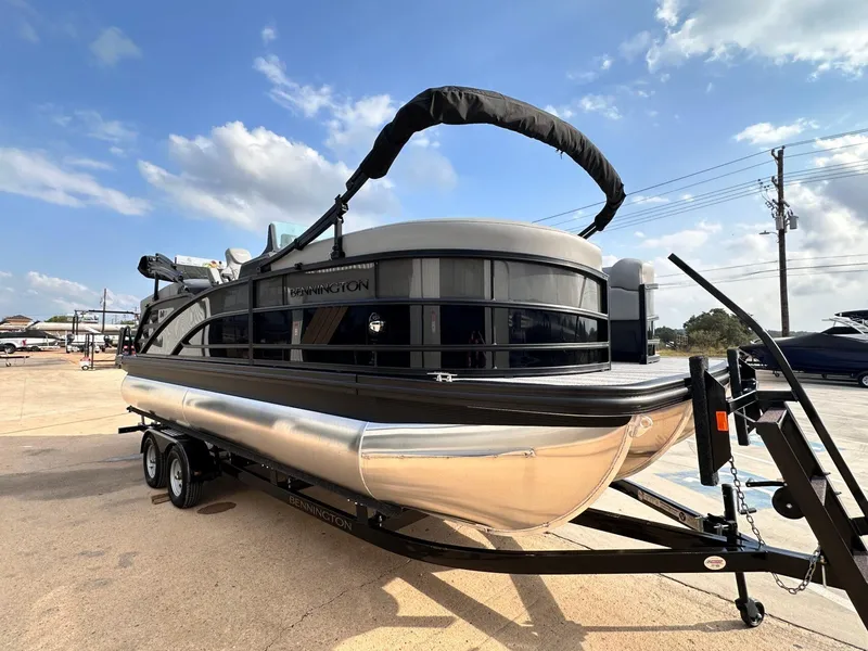 Slide: The Image of 2025 Bennington 22MFB pontoon boat on trailer under a clear blue sky. - 10