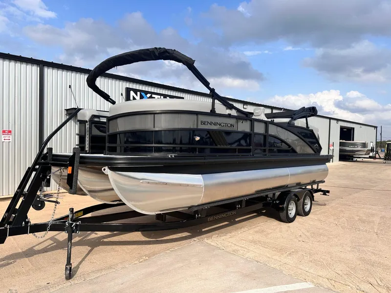 Slide: The Image of 2025 Bennington 22MFB pontoon boat on trailer, parked outside a warehouse. - 2