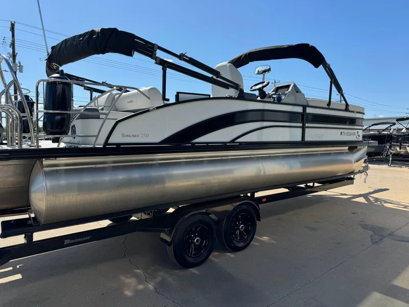 Slide: The Image of 2022 Harris Sunliner 250 pontoon boat on trailer, side view under clear blue sky. - 4