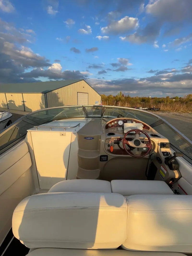 Slide: The Image of 2005 Four Winns 248 Vista boat interior with steering wheel and seating under a blue sky. - 8