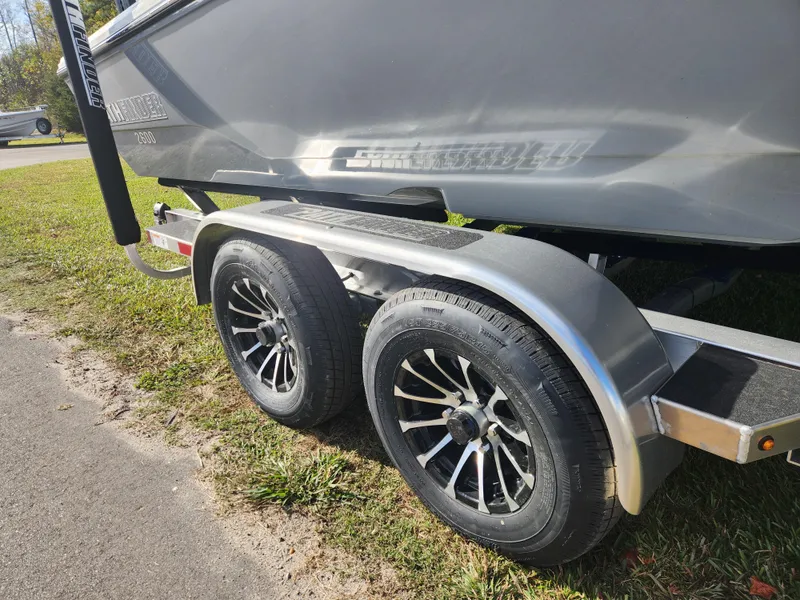 Slide: The Image of 2025 Pathfinder 2600 HPS boat trailer with dual wheels on grass. - 8