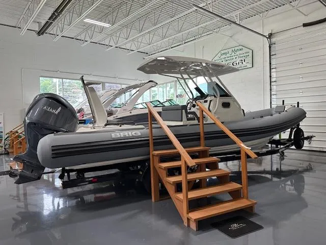 Slide: The Image of 2025 Brig Eagle 8 boat displayed indoors with wooden steps and Yamaha engine. - 2