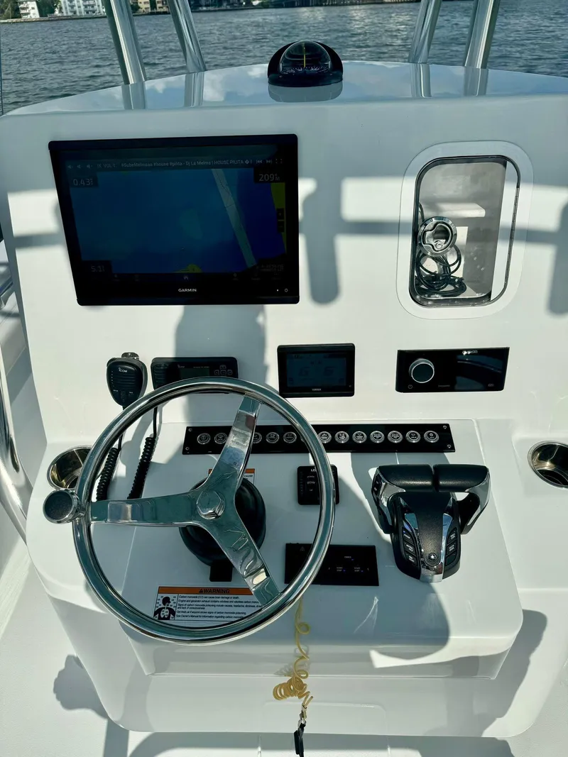 Slide: The Image of 2023 Contender Center Console boat dashboard with steering wheel and navigation controls. - 12