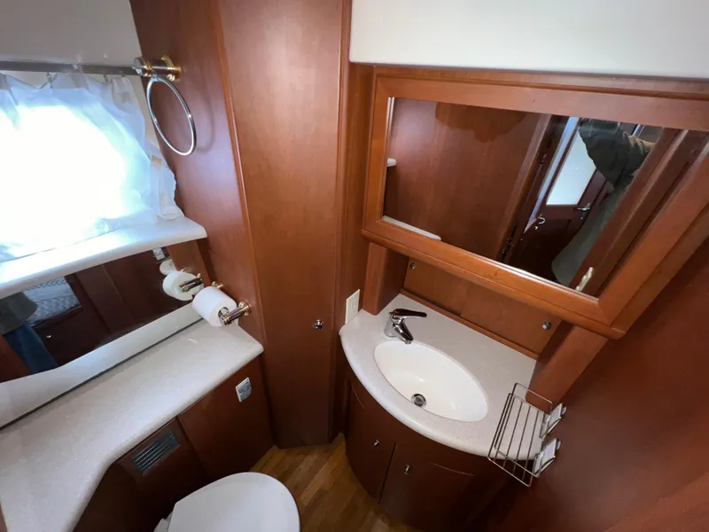 Slide: The Image of 2004 Silverton 39 Motor Yacht bathroom with sink, mirror, and wooden cabinetry. - 21