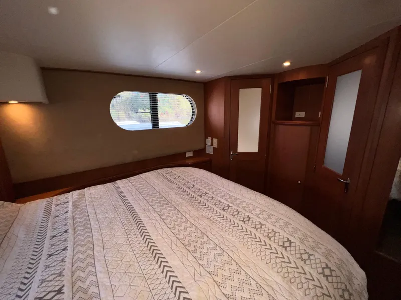 Slide: The Image of Interior of 2004 Silverton 39 Motor Yacht bedroom with patterned bedding and wooden cabinetry. - 24