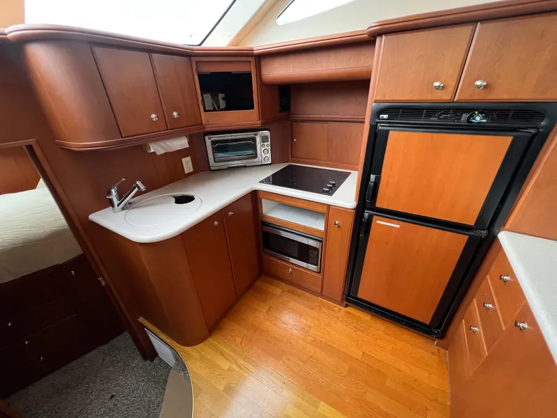 Slide: The Image of 2004 Silverton 39 Motor Yacht kitchen with wood cabinets, fridge, and appliances. - 27