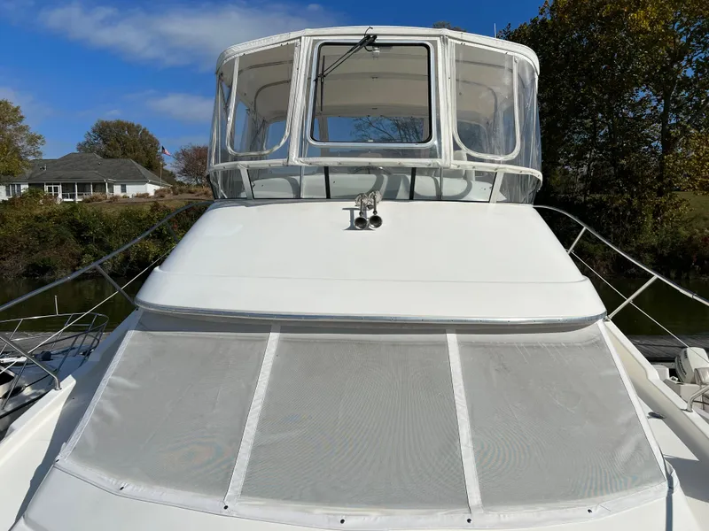 Slide: The Image of 2004 Silverton 39 Motor Yacht with enclosed flybridge, docked near trees and houses. - 8