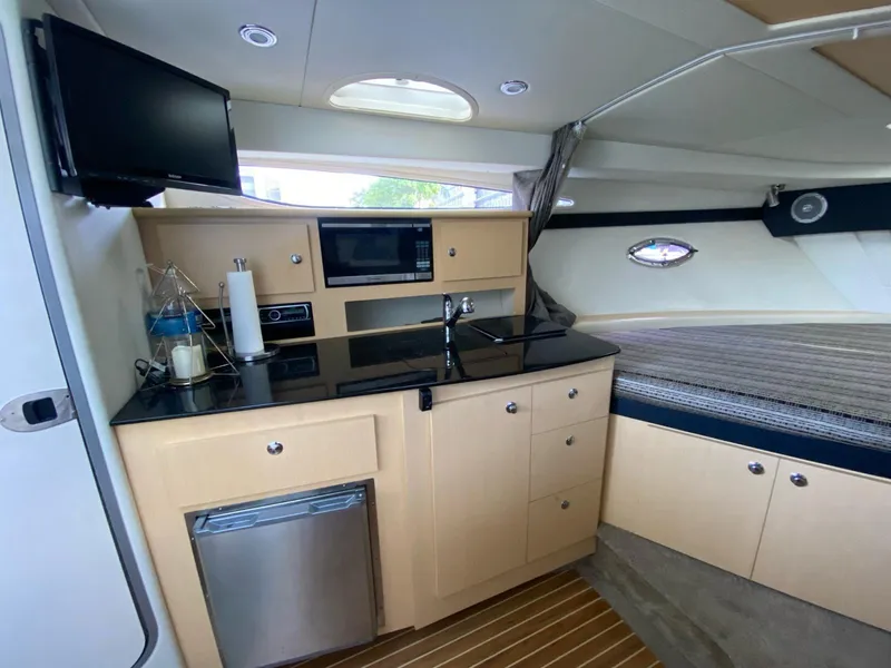 Slide: The Image of 2015 Bayliner 335 Cruiser interior with kitchenette, bed, and modern amenities. - 10