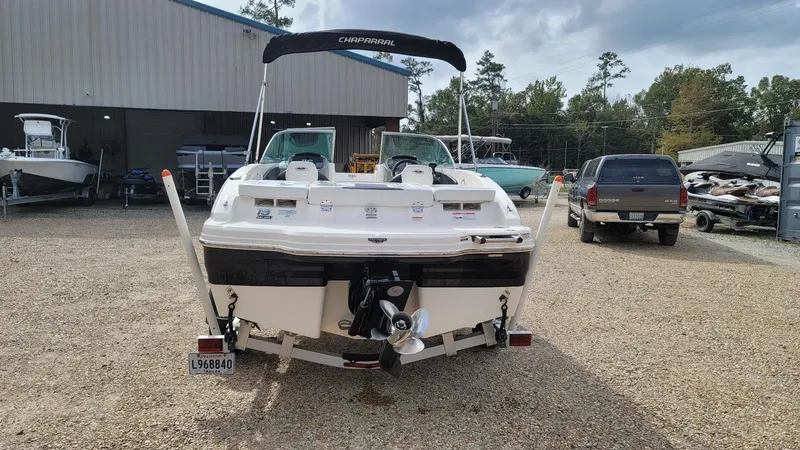Slide: The Image of 2016 Chaparral 19 H2O Sport boat parked outdoors near a warehouse. - 3