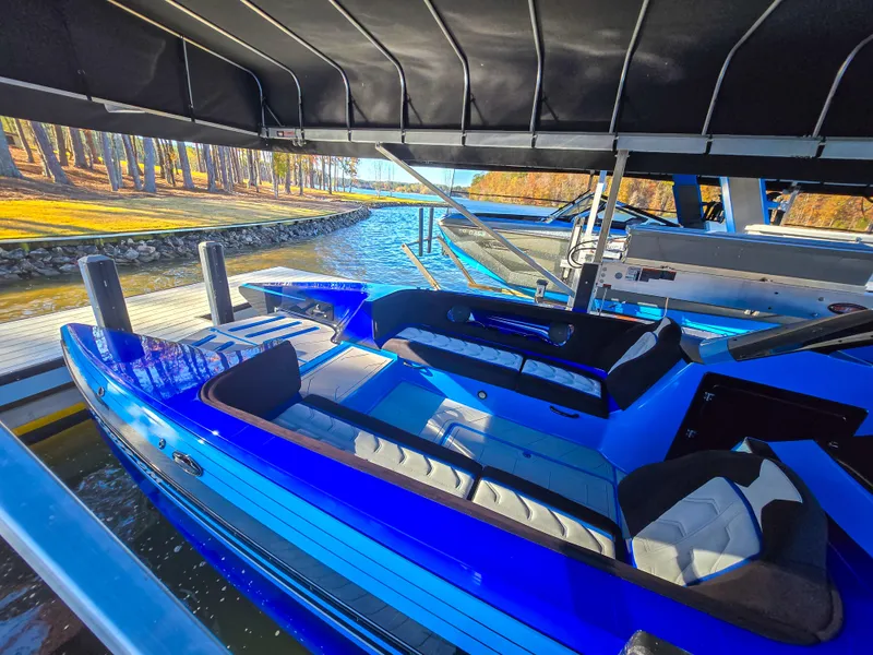 Slide: The Image of 2023 Howard 288 Sport Deck boat docked under canopy, vibrant blue exterior. - 106