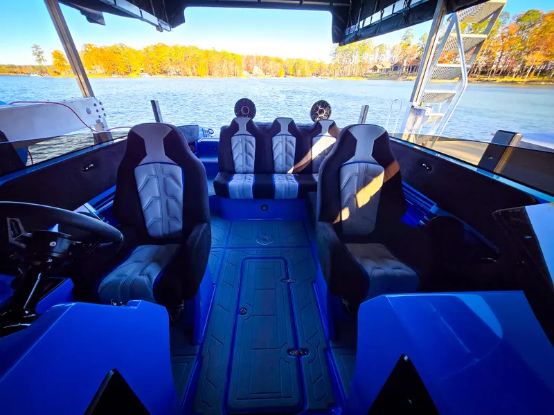Slide: The Image of 2023 Howard 288 Sport Deck boat interior with blue and black seating on a lake. - 29