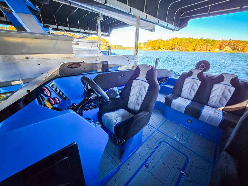 Slide: The Image of 2023 Howard 288 Sport Deck boat interior with blue and black seating on a lake. - 35