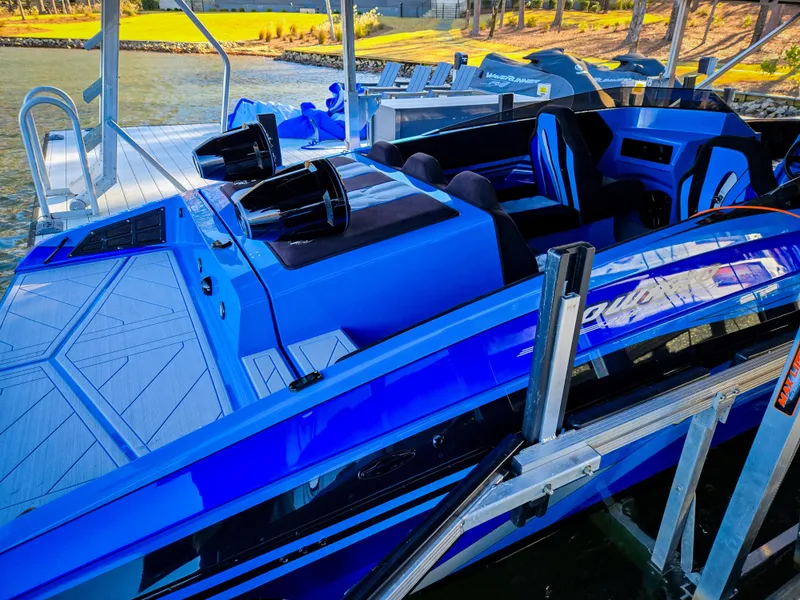 Slide: The Image of 2023 Howard 288 Sport Deck boat in vibrant blue docked at a marina. - 52