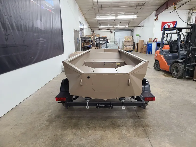 Slide: The Image of 2024 Reaper Boats 550 in warehouse, beige color, on trailer, with forklift nearby. - 3