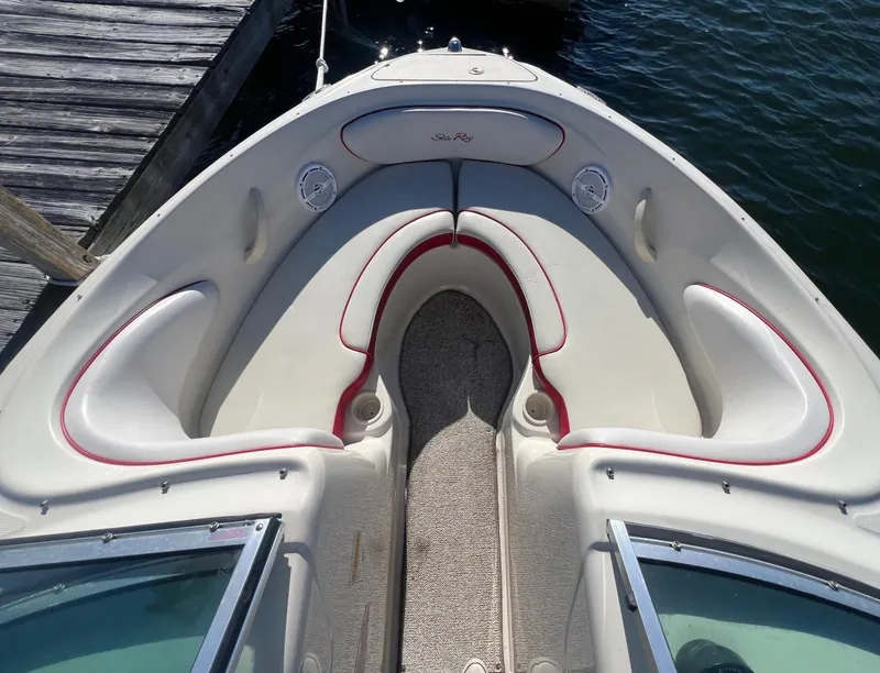 Slide: The Image of 2010 Sea Ray 205 Sport boat interior with white and red seating, docked by the water. - 13