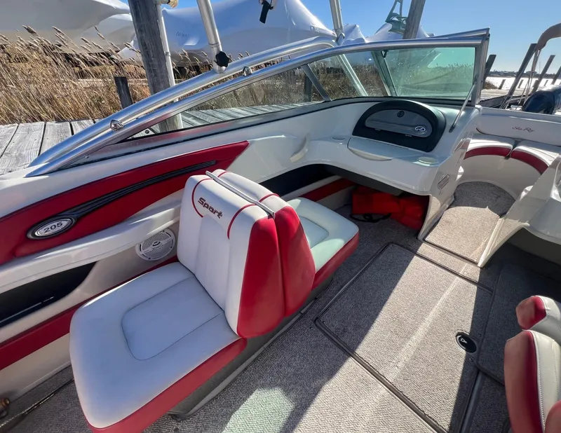 Slide: The Image of 2010 Sea Ray 205 Sport boat interior with red and white seating, dashboard, and carpeted floor. - 8