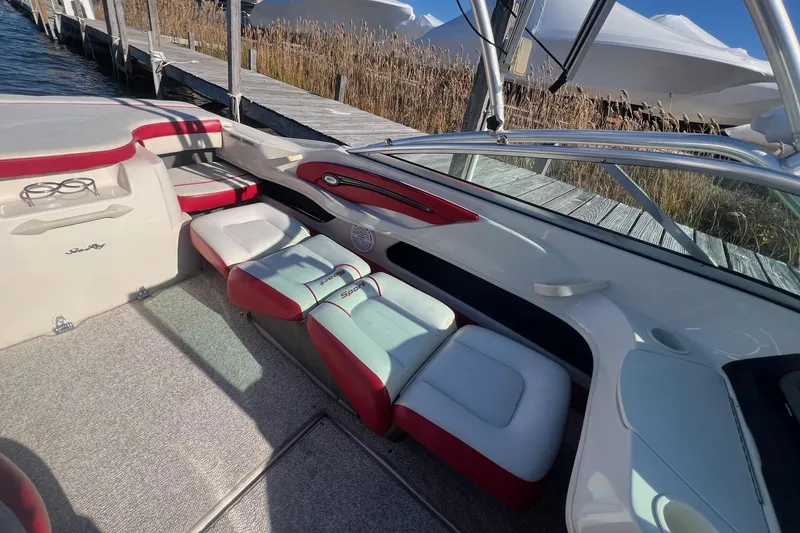 Slide: The Image of 2010 Sea Ray 205 Sport boat interior with red and white seating, docked by the water. - 9