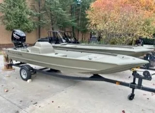 The Image of 2025 Tracker Grizzly 1648 SC boat on trailer, parked outdoors near trees. - 0