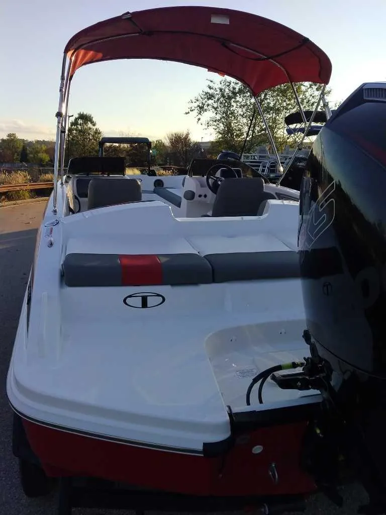Slide: The Image of 2025 Tahoe T21 boat with red canopy and outboard motor, parked outdoors. - 3