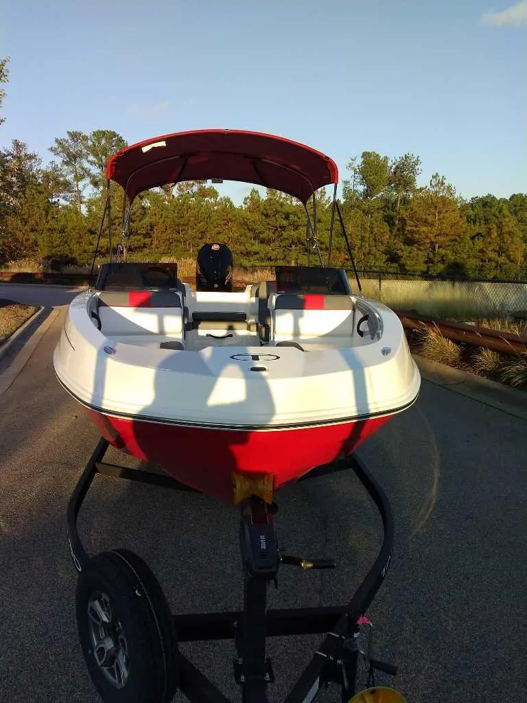 Slide: The Image of 2025 Tahoe T21 boat on trailer, red and white design, parked outdoors. - 5