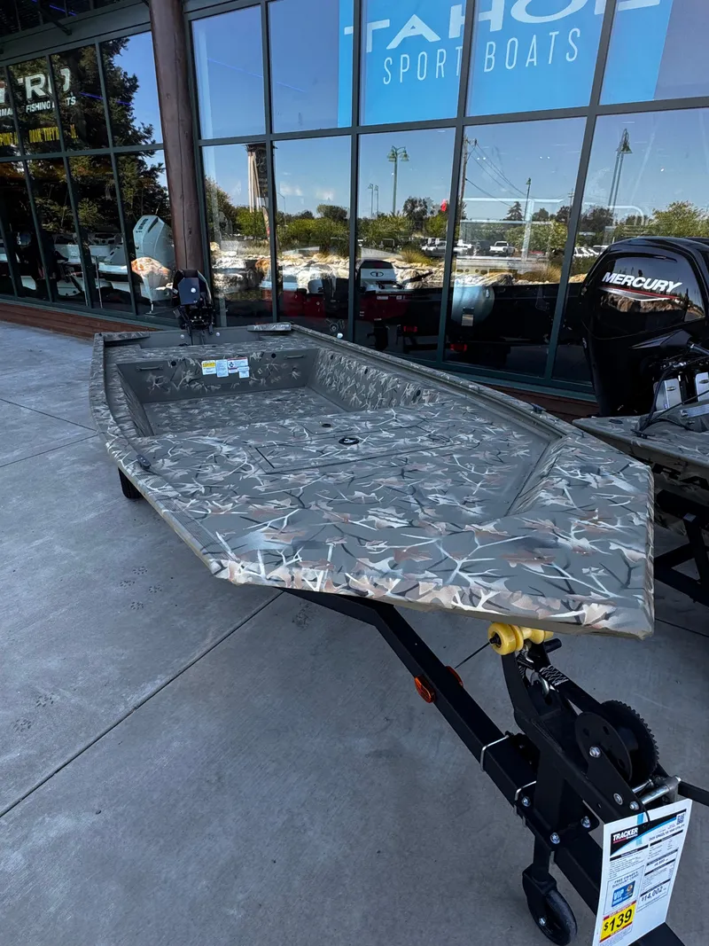 Slide: The Image of 2025 Tracker Grizzly 1648 Jon boat displayed outside Tahoe Sport Boats showroom. - 2