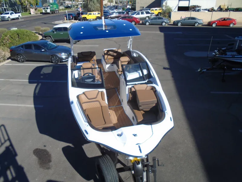 Slide: The Image of 2025 Yamaha Boats 275SD with blue canopy, parked in a lot, showcasing spacious seating. - 3