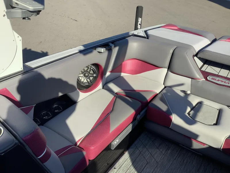 Slide: The Image of 2019 Supra SL450 boat interior with red and gray seating, speaker, and cup holders. - 16