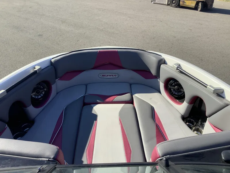 Slide: The Image of 2019 Supra SL450 boat interior with gray and red seating, speakers, and cup holders. - 22