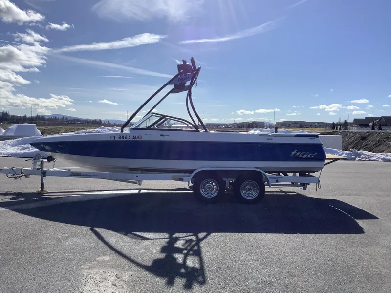 Slide: The Image of 2002 Tigé 22i boat on trailer under clear blue sky. - 1