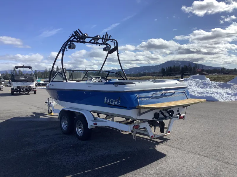 Slide: The Image of 2002 Tigé 22i boat on trailer, blue and white, with wakeboard tower, parked outdoors. - 10