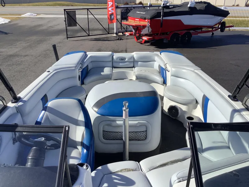 Slide: The Image of 2002 Tigé 22i boat interior with blue and white seating, parked outdoors. - 13