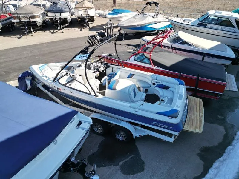 Slide: The Image of 2002 Tigé 22i boat on trailer, surrounded by other boats in a marina. - 15