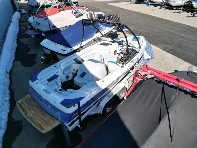 Slide: The Image of 2002 Tigé 22i boat parked on a trailer, surrounded by other boats. - 18