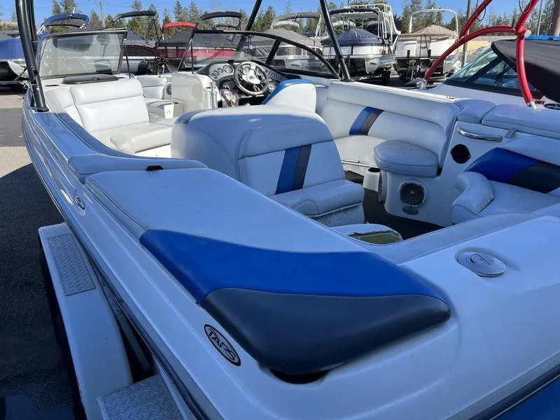 Slide: The Image of 2002 Tigé 22i boat interior with blue and white seating, parked outdoors. - 19