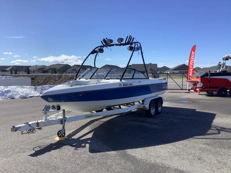 Slide: The Image of 2002 Tigé 22i boat on trailer, parked outdoors under clear blue sky. - 2