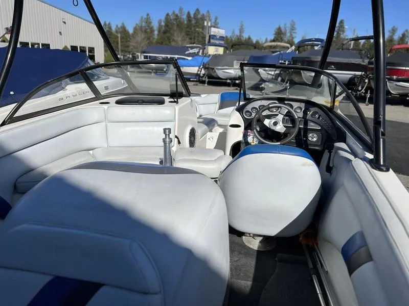 Slide: The Image of 2002 Tigé 22i boat interior with white seating and steering wheel, parked outdoors. - 21