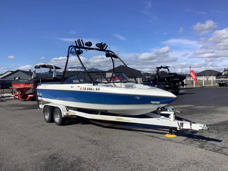 Slide: The Image of 2002 Tigé 22i boat on trailer in outdoor lot, clear sky background. - 5
