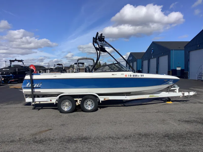 Slide: The Image of 2002 Tigé 22i boat on trailer, parked outdoors under a blue sky. - 6