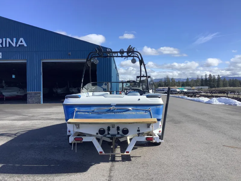 Slide: The Image of 2002 Tigé 22i boat parked outside marina, blue exterior, clear sky background. - 8