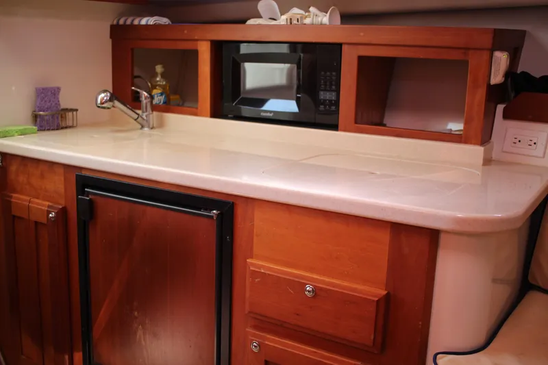 Slide: The Image of 2007 Back Cove 29 boat kitchen with wooden cabinets, microwave, and compact fridge. - 7