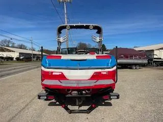 Slide: The Image of 2023 MasterCraft NXT22 boat, rear view, vibrant red and blue design, parked outdoors. - 2