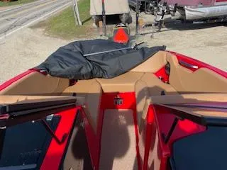 Slide: The Image of 2024 MasterCraft NXT22 boat interior with red and tan seating, parked outdoors. - 4