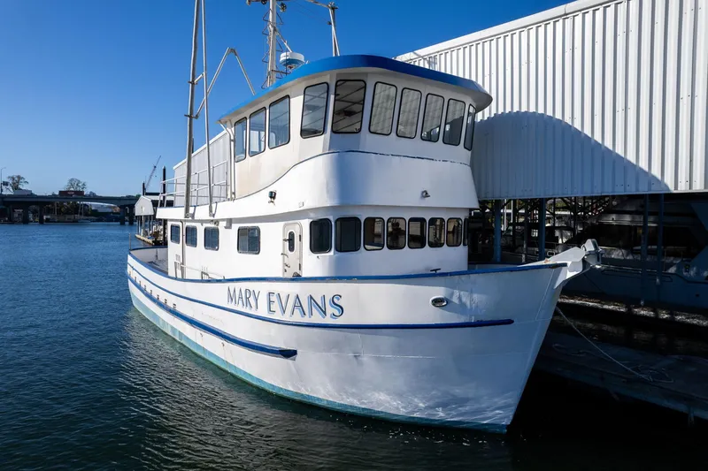The Image of A 1980 commercial troller boat named "Mary Evans" docked by a waterfront building. - 1