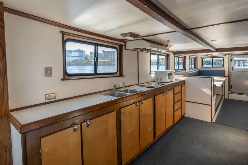 Slide: The Image of 1980 Commercial Troller interior with kitchen, wooden cabinets, and windows overlooking water. - 11