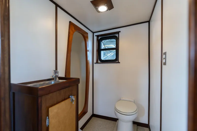 Slide: The Image of 1980 Commercial Troller bathroom with sink, toilet, mirror, and window. - 12