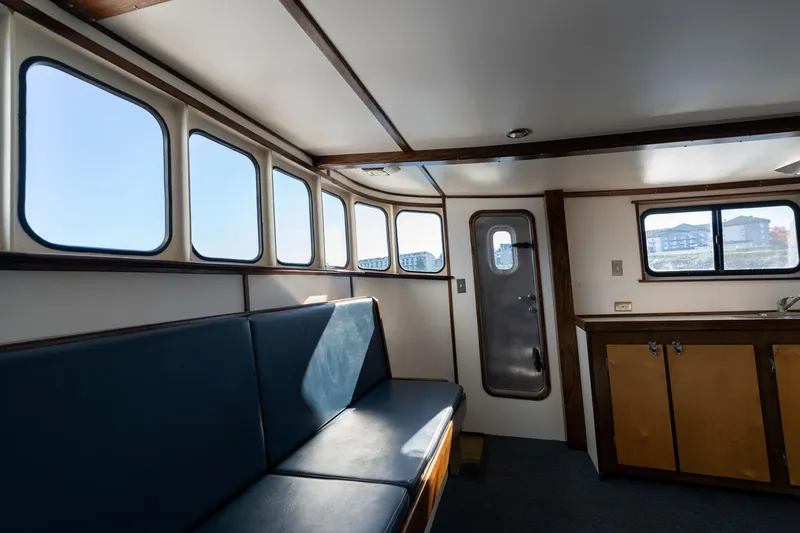 Slide: The Image of Interior of a 1980 Commercial Troller boat with blue seating and large windows. - 15