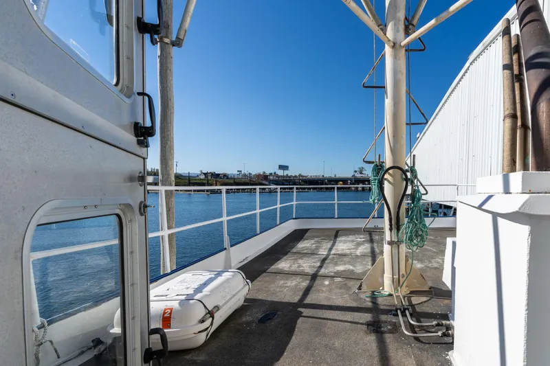 Slide: The Image of 1980 Commercial Troller deck with lifeboat, ropes, and waterfront view. - 33